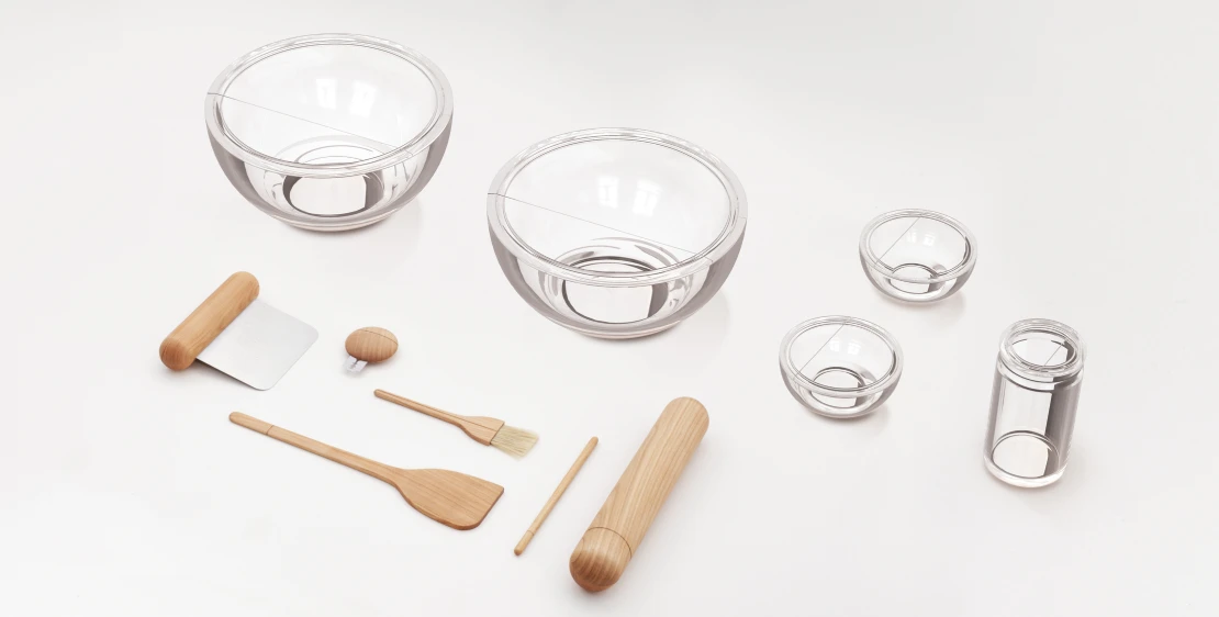 Flat lay of the bread-baking tool set: glass bowls, measures, wooden scrapers, a rolling pin and brushes on pale grey