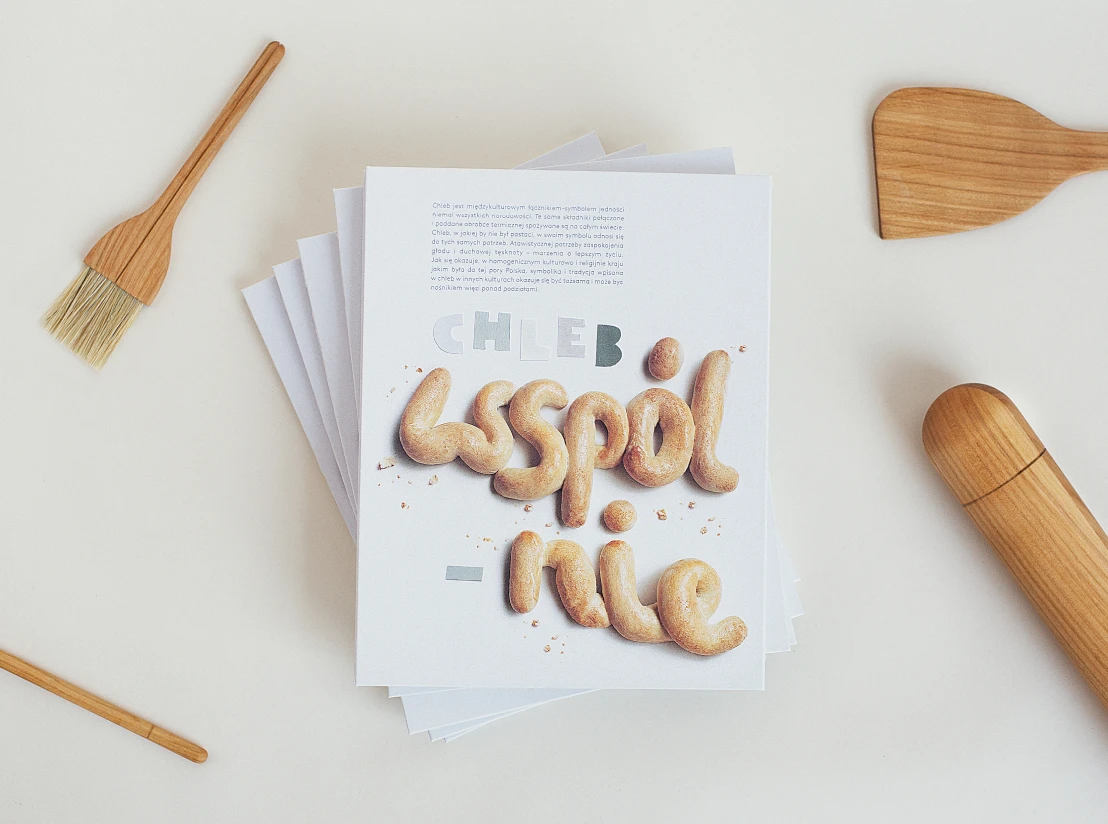 Stack of printed publications with the dough-lettering cover, next to a wooden spatula, brush and honey dipper