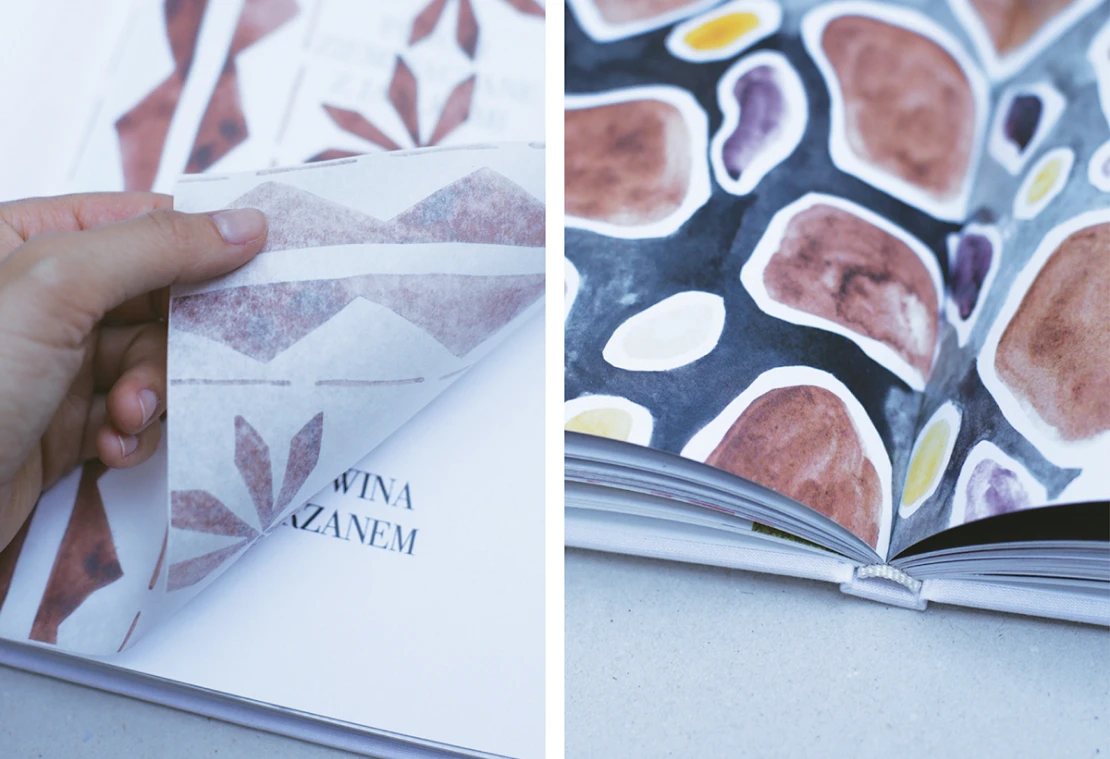 Hand lifting a semi-transparent parchment sheet printed with a brown folk ornament over a chapter title, beside a spread of watercolour stones